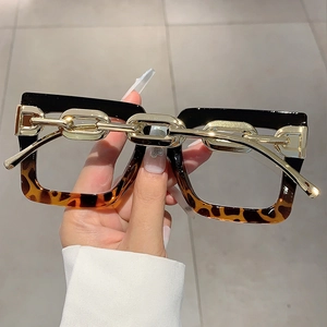 Detail view of square frame glasses with gold metal chain accent and tortoiseshell design