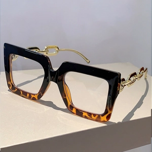 Detail of square glasses with leopard print frame and golden metal chain temples