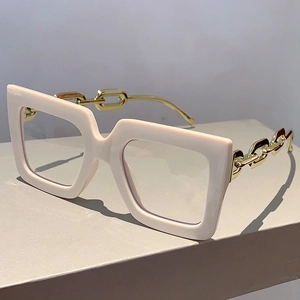 Detail of cream square oversized glasses with gold chain design temples on a display stand