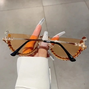 Detail of half-frame sunglasses with amber lenses and crystal-studded gold metal wave trim