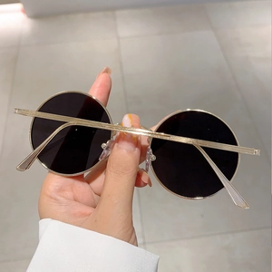 Detailed view of retro round sunglasses with gold metal frame and dark lenses