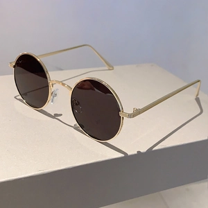 Detail of vintage round sunglasses with gold metal frame and dark brown lenses