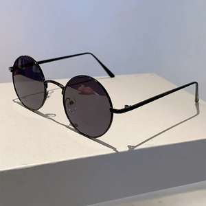 Detail shot of vintage round sunglasses with black metal frame on a white minimalist base