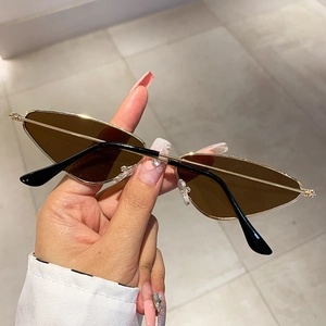 Detail of cat eye sunglasses with golden metal frame and brown lenses held in hand