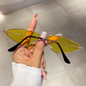 Detailed close-up of yellow lenses and slim gold metal frame of small trendy sunglasses