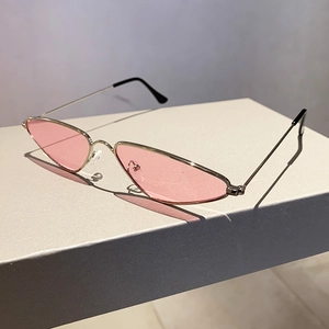Detail of slim metal sunglasses with pink translucent lenses on a modern gray platform