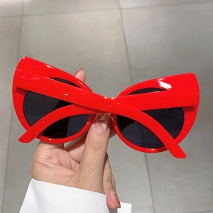Detail view of bold red cat-eye sunglasses with thick glossy frames and dark lenses