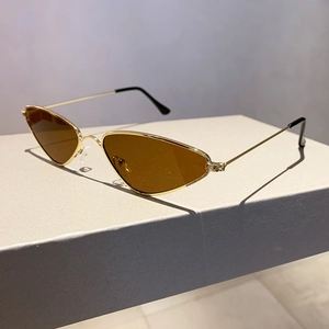 Detail of triangle metal sunglasses with golden frame and dark brown lenses in a display box