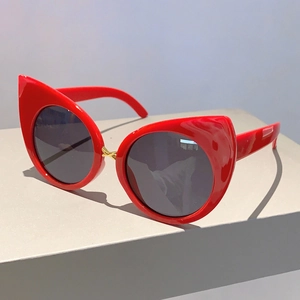 Side view of red cat-eye sunglasses with golden cross metal hinge detail and dark lenses