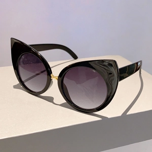 Detail of cat eye sunglasses featuring gold cross bridge accents and gradient lenses
