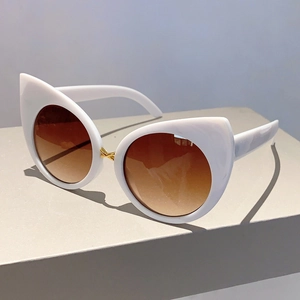 Detail of white cat eye sunglasses with brown gradient lenses and gold metal bridge