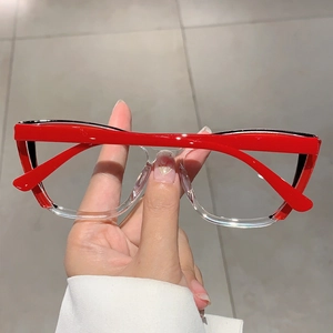 Dettaglio della montatura cat-eye bicolore rosso e trasparente tenuta in mano