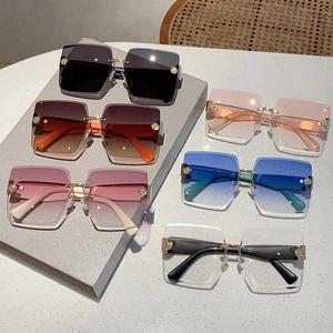 Detail view of colorful frameless oversized sunglasses with gold floral corner accents