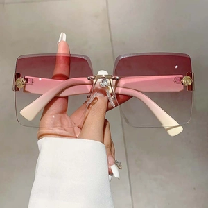 Detail of rimless gradient pink sunglasses featuring rose floral hinge and crystal heart