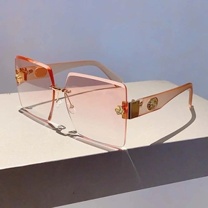 Detailed shot of rimless square sunglasses with pink gradient lenses and golden rose decor