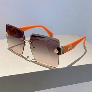 Detail of rimless square sunglasses with gradient brown lenses and orange stems
