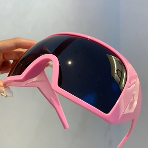 Détail de lunettes de soleil Y2K roses avec de larges verres noirs enveloppants