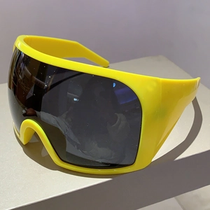 Détail de lunettes de soleil Y2K futuristes avec monture jaune et large verre monobloc