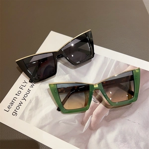 Detail view of cat-eye sunglasses with gold metal trim on leather and magazine