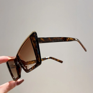 Close-up of oversized tortoiseshell frame with gold metal trim and brown gradient lenses