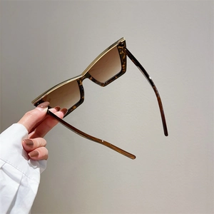 Detailed close-up of tortoise shell cat-eye sunglasses with golden metal top trim and brown lenses