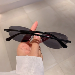 Gros plan de lunettes de soleil ovales sans monture avec verres noirs et métal fin