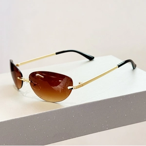 Détail de lunettes de soleil ovales sans monture Y2K avec verres dégradés bruns et branches dorées