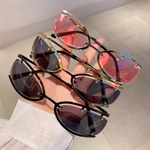 Gros plan de lunettes de soleil ovales Y2K sans monture en rose et gris avec clous