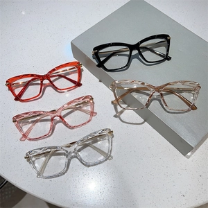 Detail view of multi-faceted cat-eye glasses frames in five colors on a textured surface