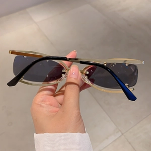Détail de lunettes de soleil Y2K sans monture avec cadre doré ajouré et verres œil-de-chat