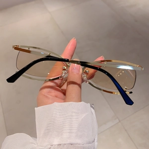 Détail de lunettes de soleil ovales sans bord avec monture dorée évidée et verres bruns
