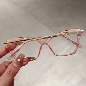 Detail of pink polygon frames with gold metal accents held in hand for close-up view