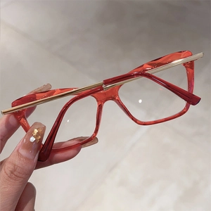 Detail of red translucent cat-eye frames with elegant gold metal temple accents