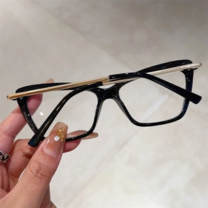 Macro detail of black square frame glasses with gold metal bar accents and clear lenses