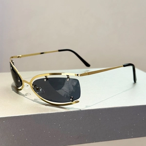 Détail de lunettes de soleil Y2K futuristes avec monture dorée et rivets décoratifs