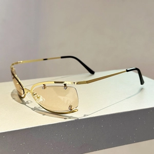 Détail de lunettes Y2K sans monture dorées avec lentilles ambre et décorations strass