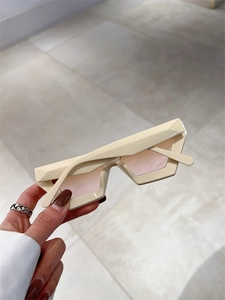 Détail de lunettes de soleil géométriques crème avec des verres rose clair transparents