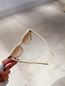 Détail de lunettes de soleil rétro géométriques à monture crème et verres rose clair