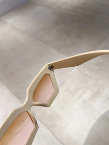 Détail de la charnière en métal sur lunettes œil de chat crème avec verres roses