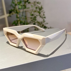 Vue latérale macro de lunettes de soleil pentagonales avec monture crème et verres dégradés