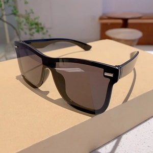 Detail of black rimless sunglasses with silver metal accents on craft paper box