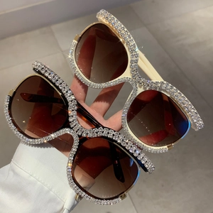 Close-up of oversized rhinestone sunglasses with white crystal frames and gradient lenses
