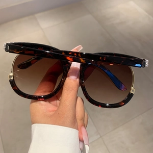 Detailed macro view of tortoiseshell oversized sunglasses with gold metal accents
