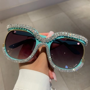 Close-up of luxury oversized mint green sunglasses with hand-set rhinestones and purple lenses