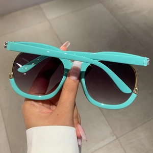 Close-up of Tiffany blue oversized sunglasses with gradient lenses and rhinestone details