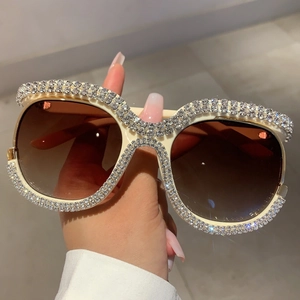 Detailed view of oversized cream sunglasses with luxury rhinestone encrusted frames