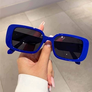 Detail of trendy rectangle sunglasses featuring a bright blue frame and dark grey lenses