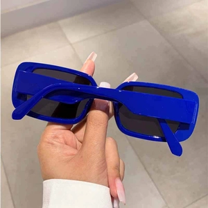 Detailed view of hand-held bright blue rectangular sunglasses with sleek polished frames