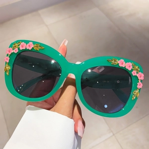 Detail of green cat eye sunglasses with handmade pink floral and gold leaf accents