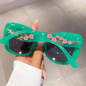 Detail of green cat-eye sunglasses with 3D pink flowers, gold leaves and rhinestones
